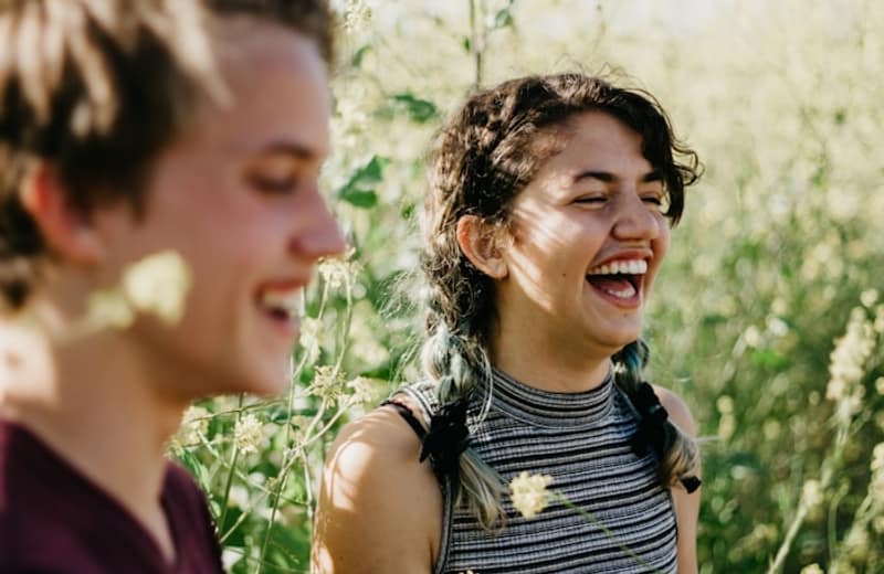 Two friends laughing outdoors in the sun
